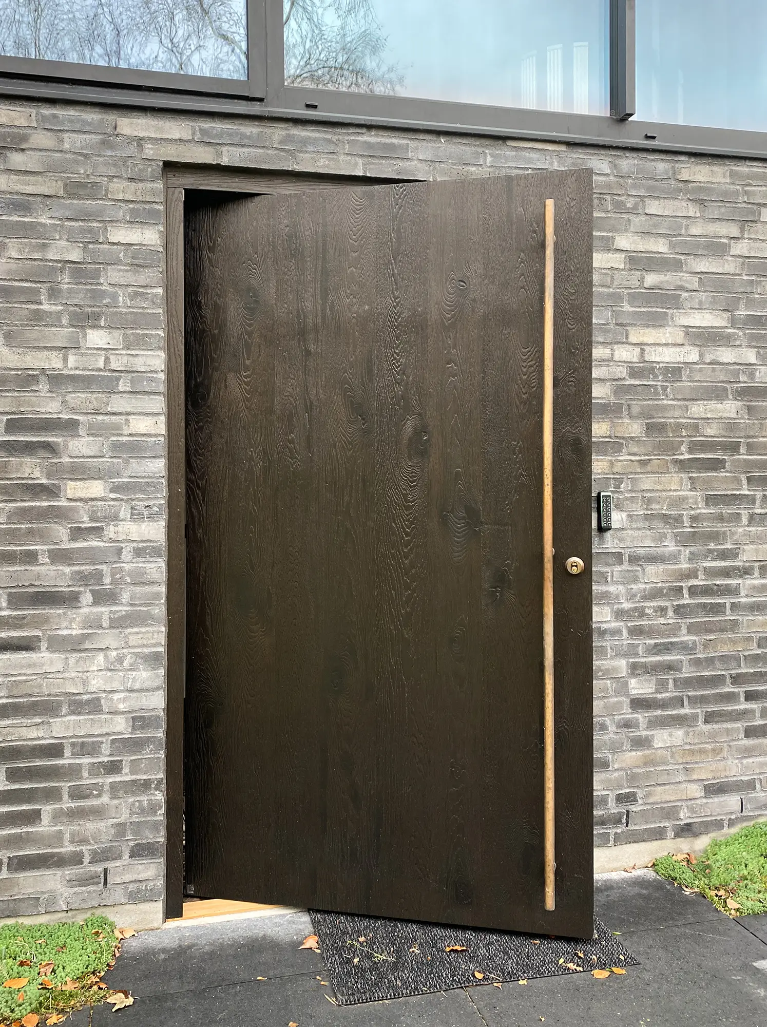 Exterior door in solid oak with pivot construction and bronze pull handle.